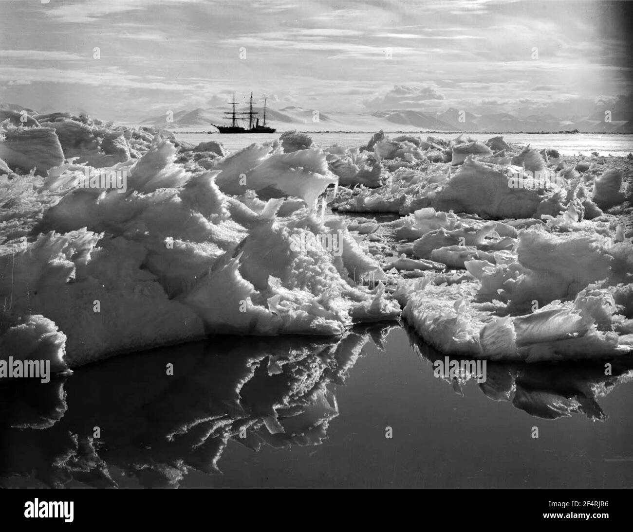 „Tod eines Eisbergs“, wunderschöne Eisspiegelungen im Wasser mit dem Terra Nova-Schiff im Hintergrund. Fotografiert von Herbert Ponting Stockfoto