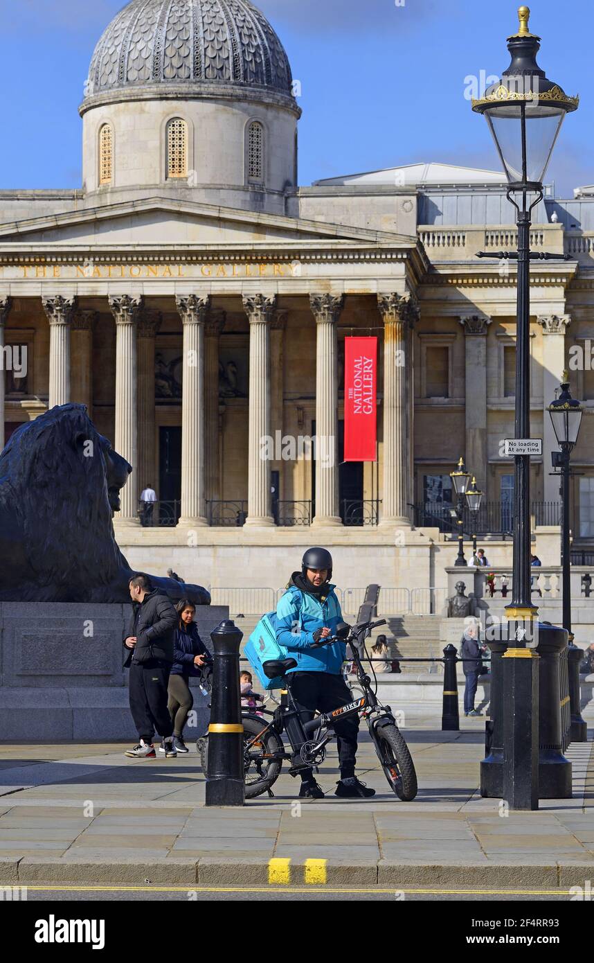London, England, Großbritannien. Trafalgar Square. Lieferoo Lieferer auf einem EFF Elektrofahrrad. National Gallery dahinter Stockfoto