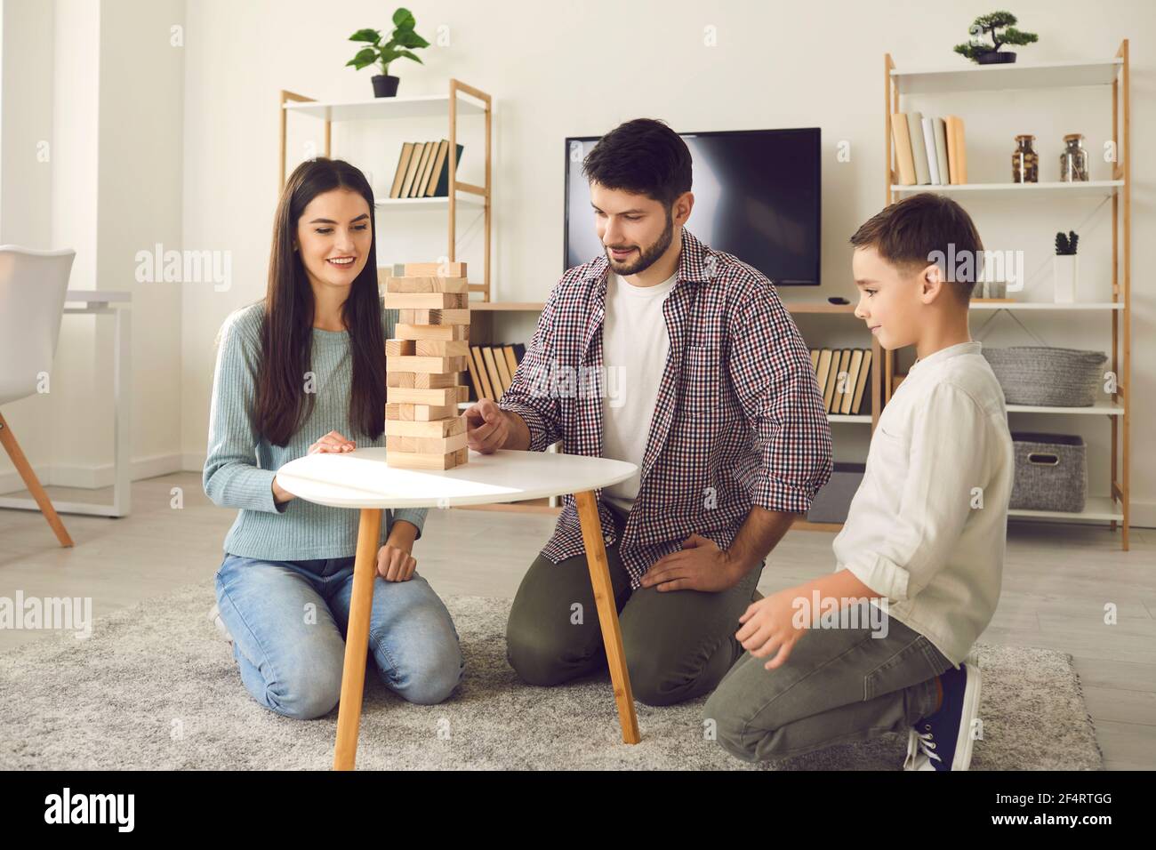 Glückliche Mutter und Vater verbringen Zeit mit Sohn an ihrem Tag frei spielen Brettspiel. Stockfoto