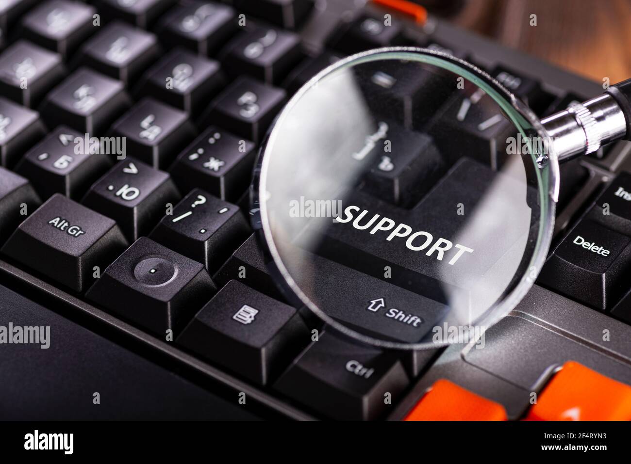 Vergrößerungsglas auf Tastenunterstützung für schwarze Computertastatur. Technischer Support. Stockfoto