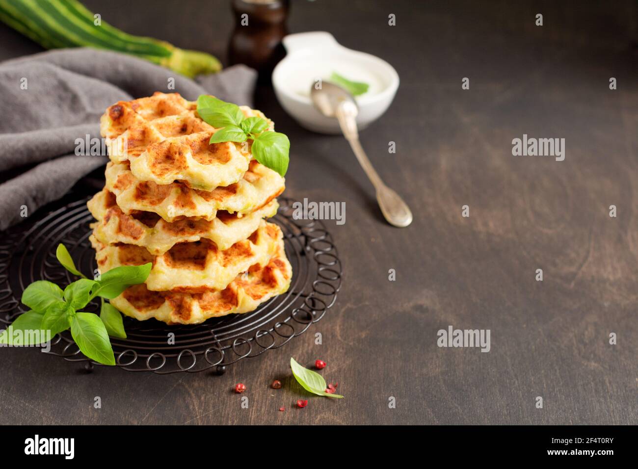 Hausgemachte Zucchini Waffeln Stapel mit Käse, Sause und Blatt Basilikum auf alten Holz dunklen Hintergrund. Konzept der Keto Ernährung Lebensmittel. Selektiver Fokus Stockfoto