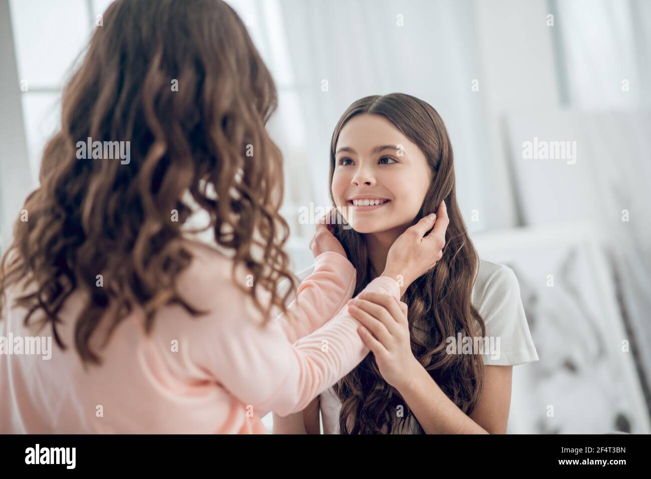 Mutter berührt ihre glücklich aussehende Töchter Haar Stockfoto