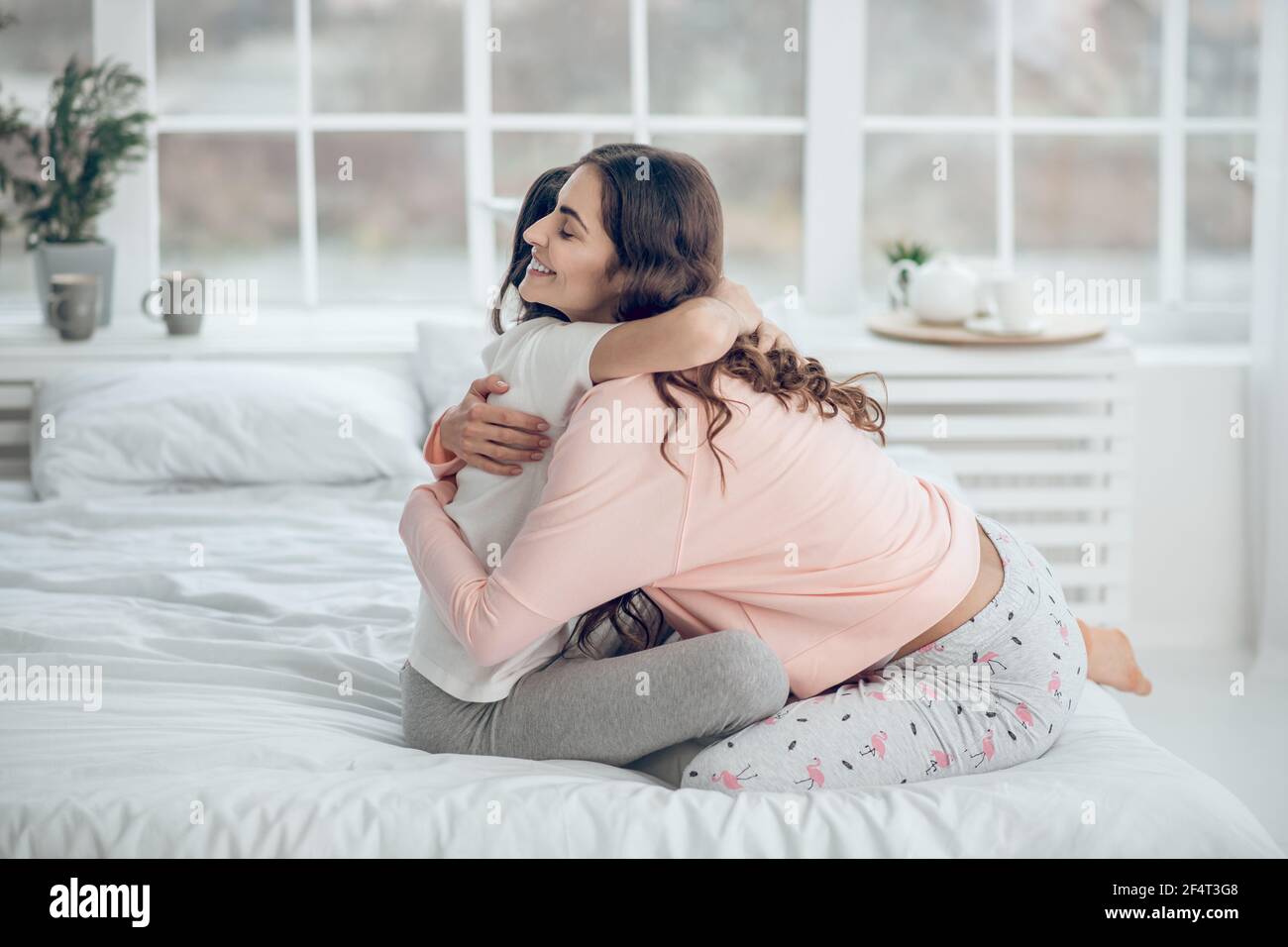 Mutter und Tochter umarmen sich morgens auf dem Bett Stockfoto