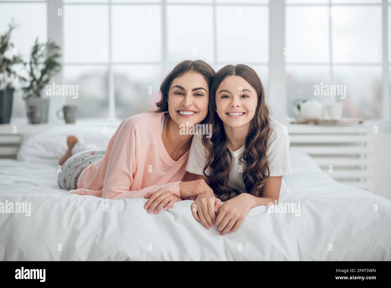 Ähnliche Mutter und Tochter liegen auf den Mägen auf dem Bett Stockfoto