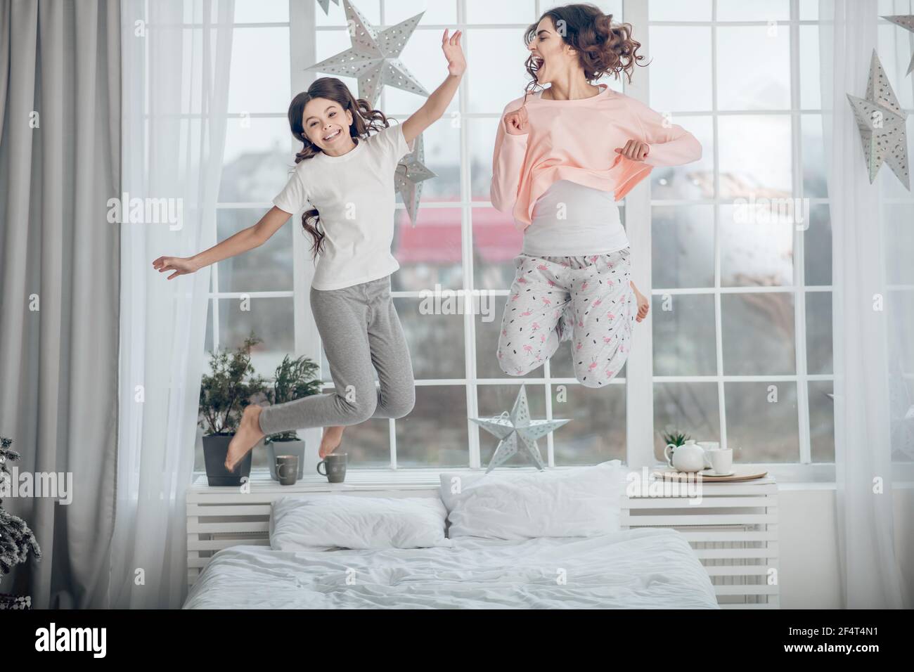 Glücklich energetische Mutter mit Tochter springen auf Bett Stockfoto