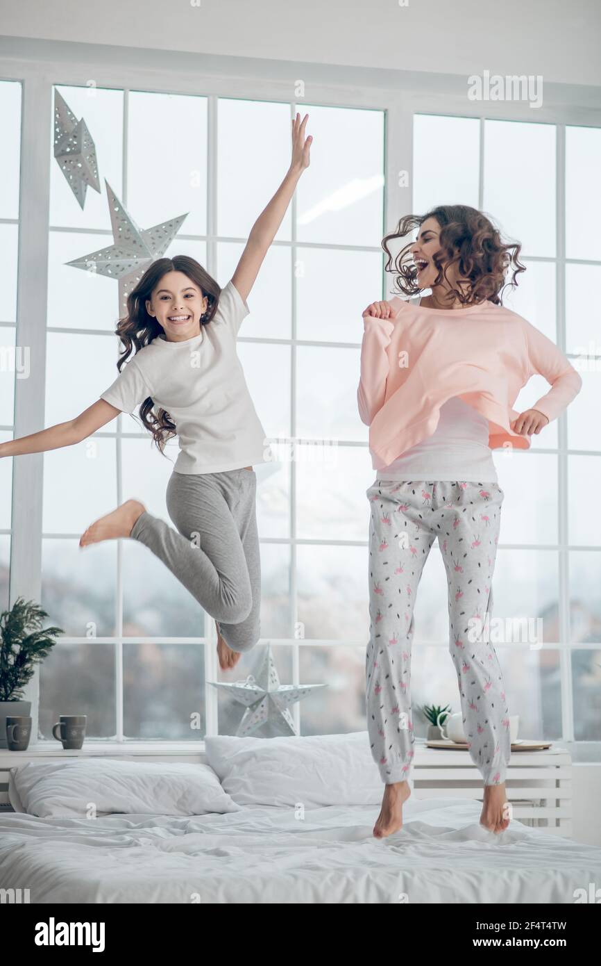 Frau mit Teenager-Mädchen springen auf Bett zu Hause Stockfoto