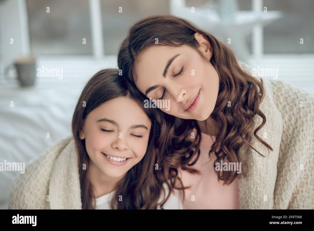 Lächelnde Tochter mit Mama mit geschlossenen Augen Stockfoto