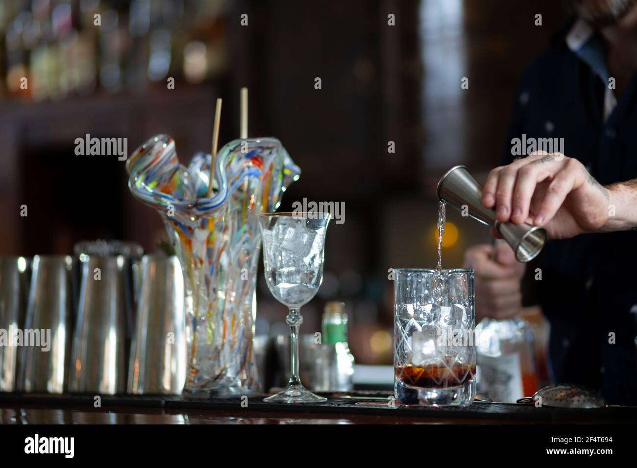 Der Barkeeper gießt Alkohol aus dem Glas in einen schicken Kristall Glaswaren im Vancouver Bar Restaurant Stockfoto