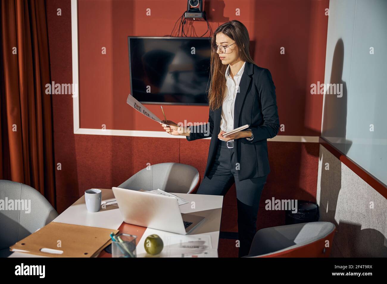 Junge Frau konzentrierte sich auf eine technische Zeichnung in der Hand Stockfoto