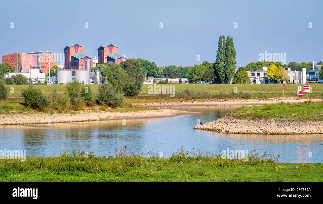 Niederländische Landschaft mit dem Fluss IJssel und seinen Auen in der Nähe der Stadt Deventer Hanze. Wohngebäude und Industriegebäude sind zu sehen. Stockfoto