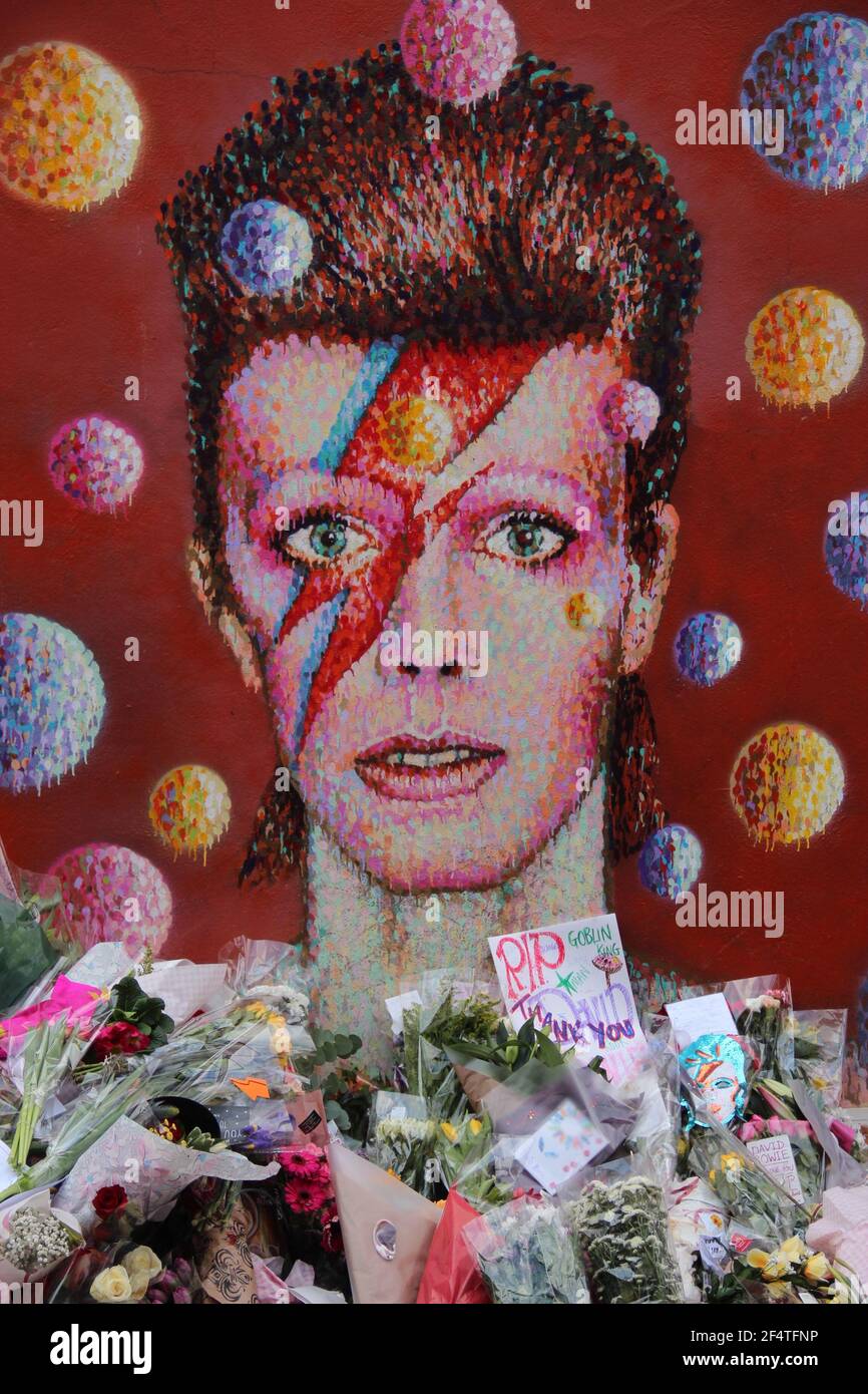 LONDON, UK - JANUAR 12 2016: Blumen, die David Bowie Fans nach seinem Tod auf dem Wandgemälde des Musikers in Brixton gelegt haben Stockfoto