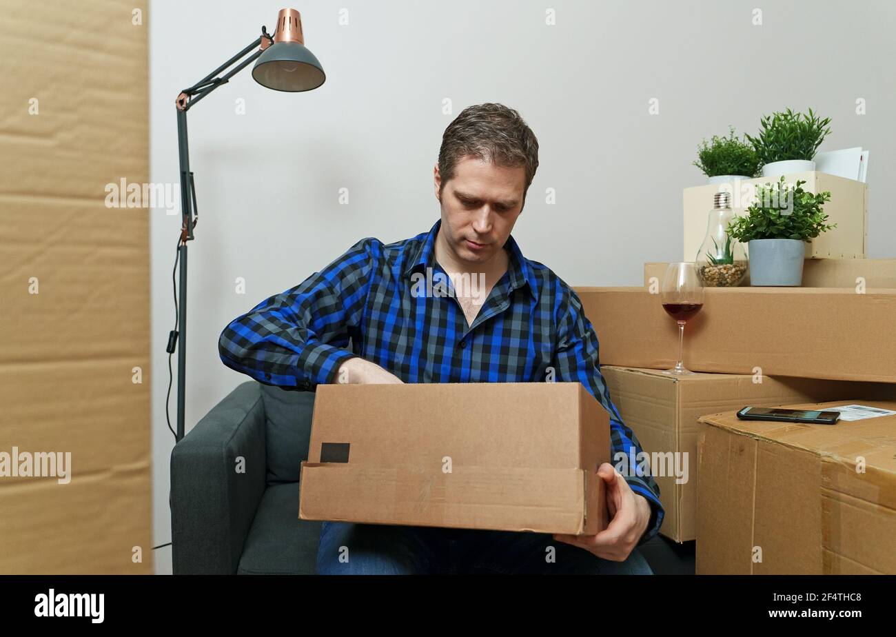Mann, der sein Zeug in eine neue Wohnung auspackte. Stockfoto