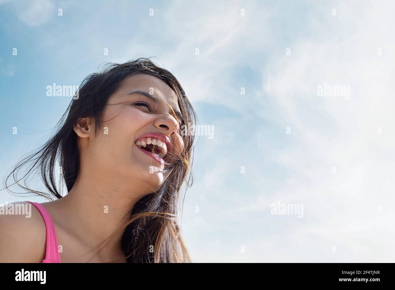 EINE JUNGE FRAU, DIE LACHT UND EINEN SONNIGEN TAG GENIESST Stockfoto