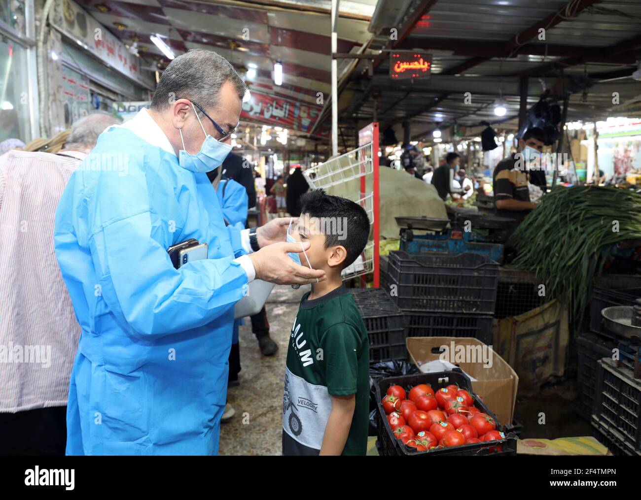 Bagdad. März 2021, 23rd. Ein Gesundheitshelfer hilft einem Kind bei der Gesichtsmaske während einer Sensibilisations- und Erkennungskampagne COVID-19 in Bagdad, Irak, am 23. März 2021. Das irakische Gesundheitsministerium berichtete am Montag über 4.655 neue COVID-19 Fälle, was die landesweite Gesamtzahl auf 798.547 erhöht. Quelle: Khalil Dawood/Xinhua/Alamy Live News Stockfoto