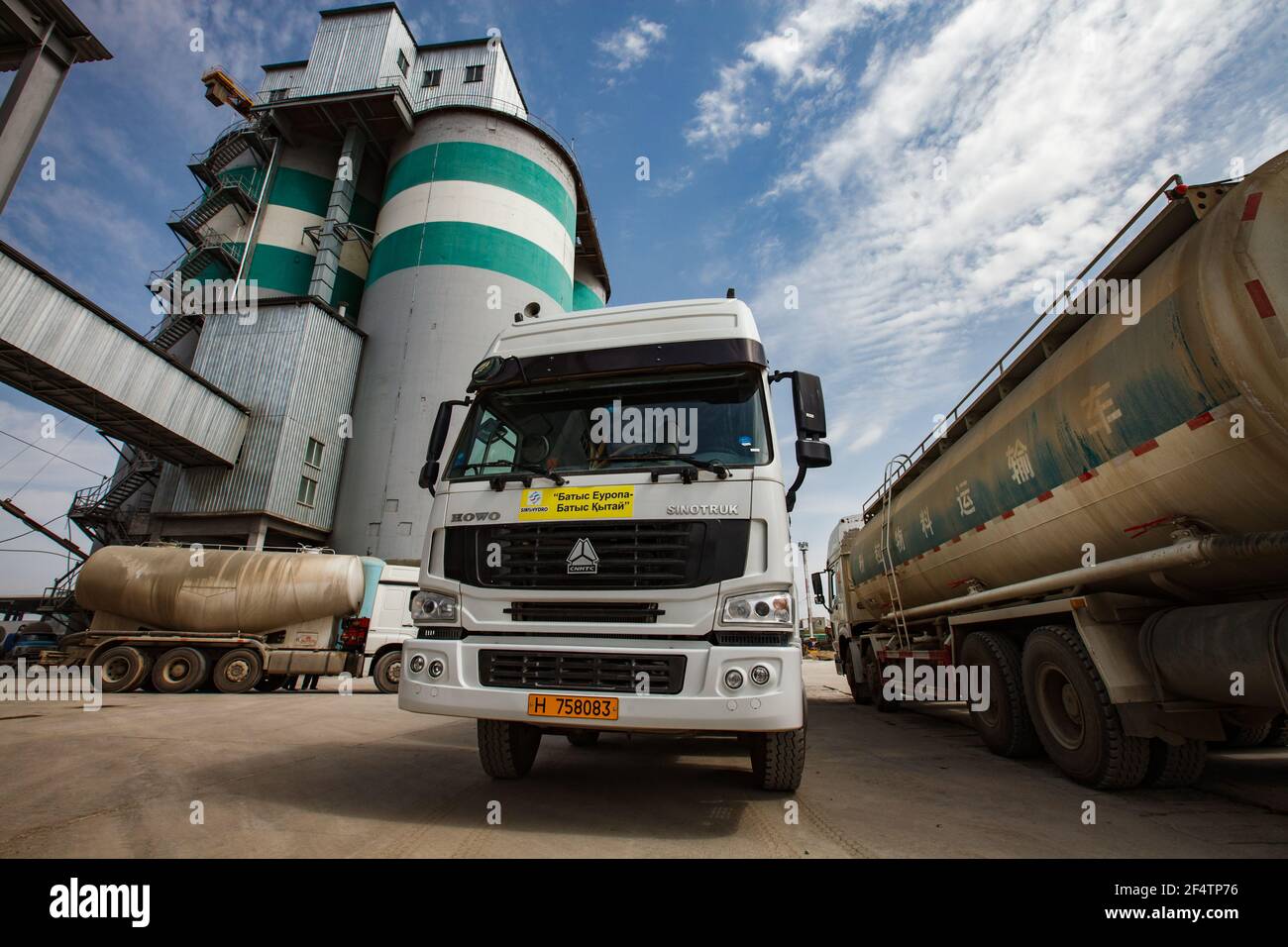 Standard-Zementwerk. Zementwagen mit trockenem Zement auf Betonsilos und blauem Himmel mit Wolken Hintergrund. Stockfoto