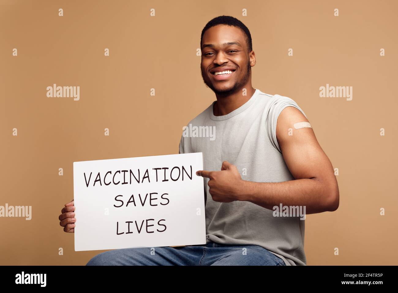Geimpfte Black Man Holding Poster Werbung Coronavirus Impfung, Beige Hintergrund Stockfoto