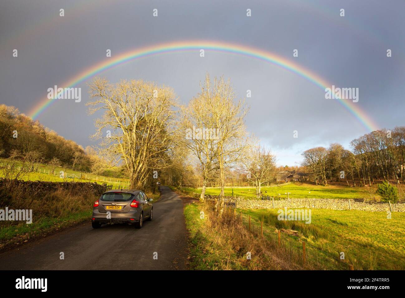 Ein Regenbogen über einer Landstraße unter Little Mell fiel im Lake District, Großbritannien. Stockfoto