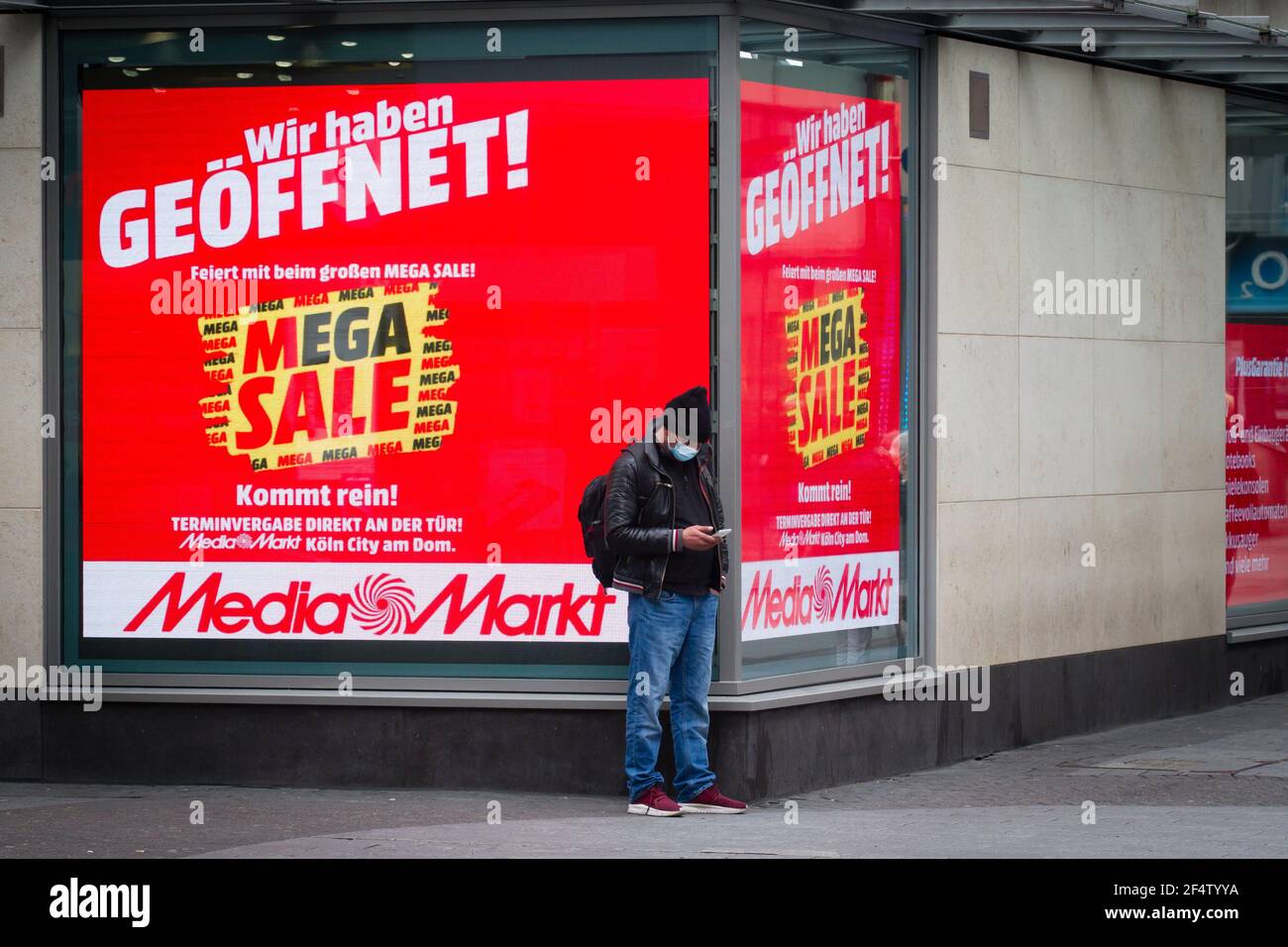 Mann, der vor einem Media Markt-Werbedisplay auf der Einkaufsstraße hohe Straße, Köln, steht. Mann steht vor einem Werbedisplay Stockfoto