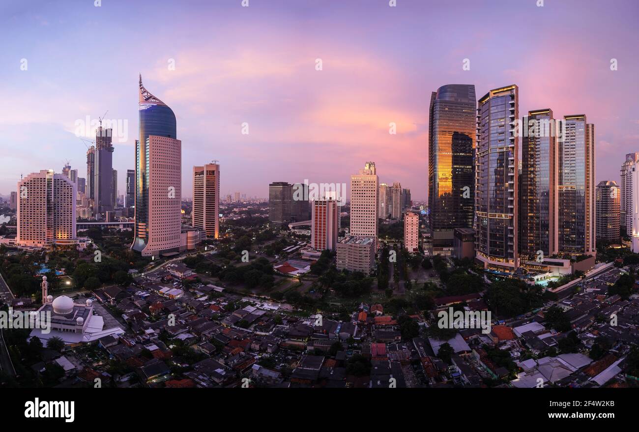 Atemberaubender Sonnenuntergang über der Skyline von Jakarta, wo moderne Büro- und Wohntürme im Kontrast zum traditionellen Dorf Kampung stehen, das in Indonesien liegt Stockfoto