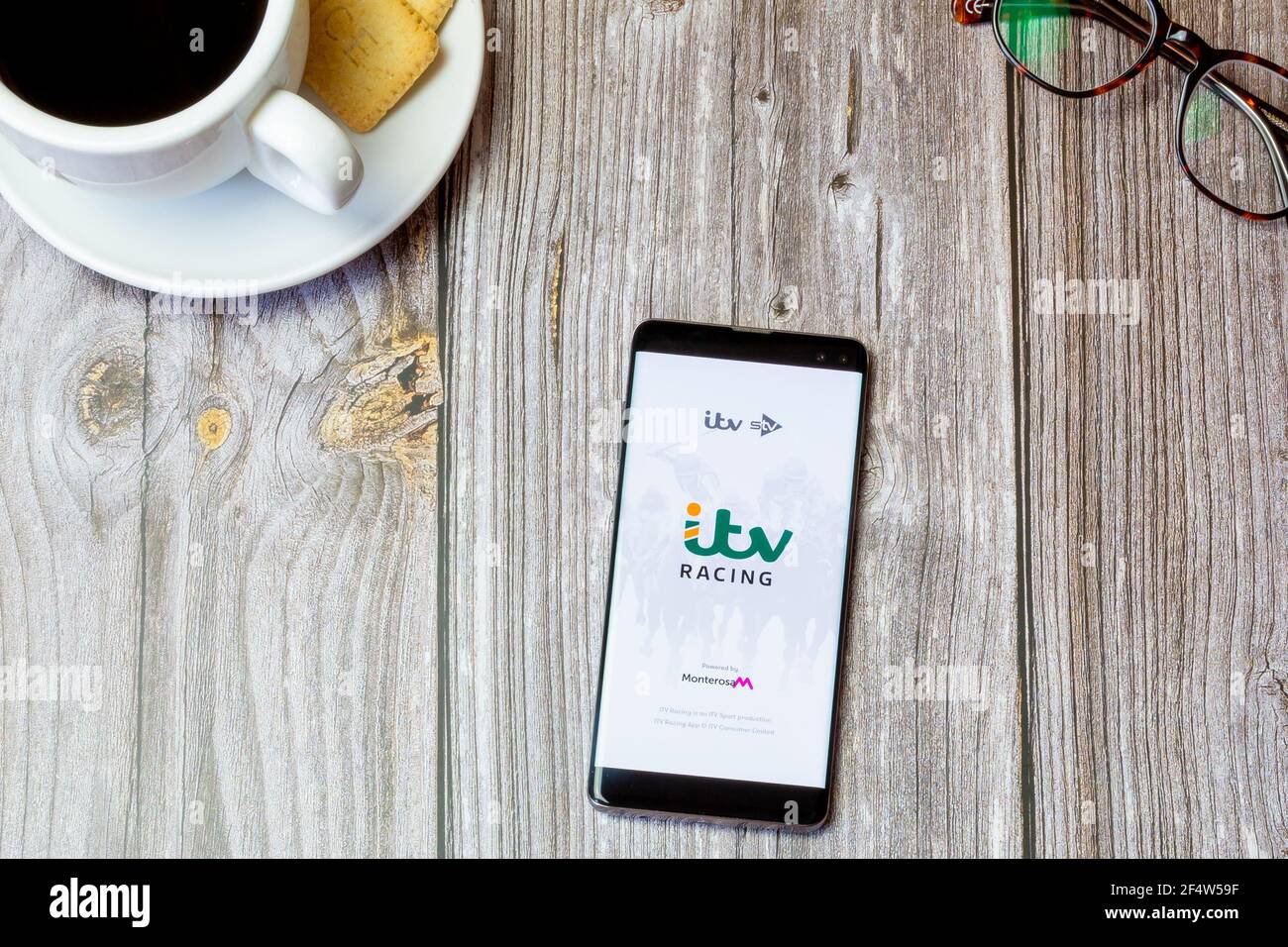 Ein Handy oder Handy auf einem Holz gelegt Tabelle mit der ITV Racing App auf dem Bildschirm geöffnet Stockfoto