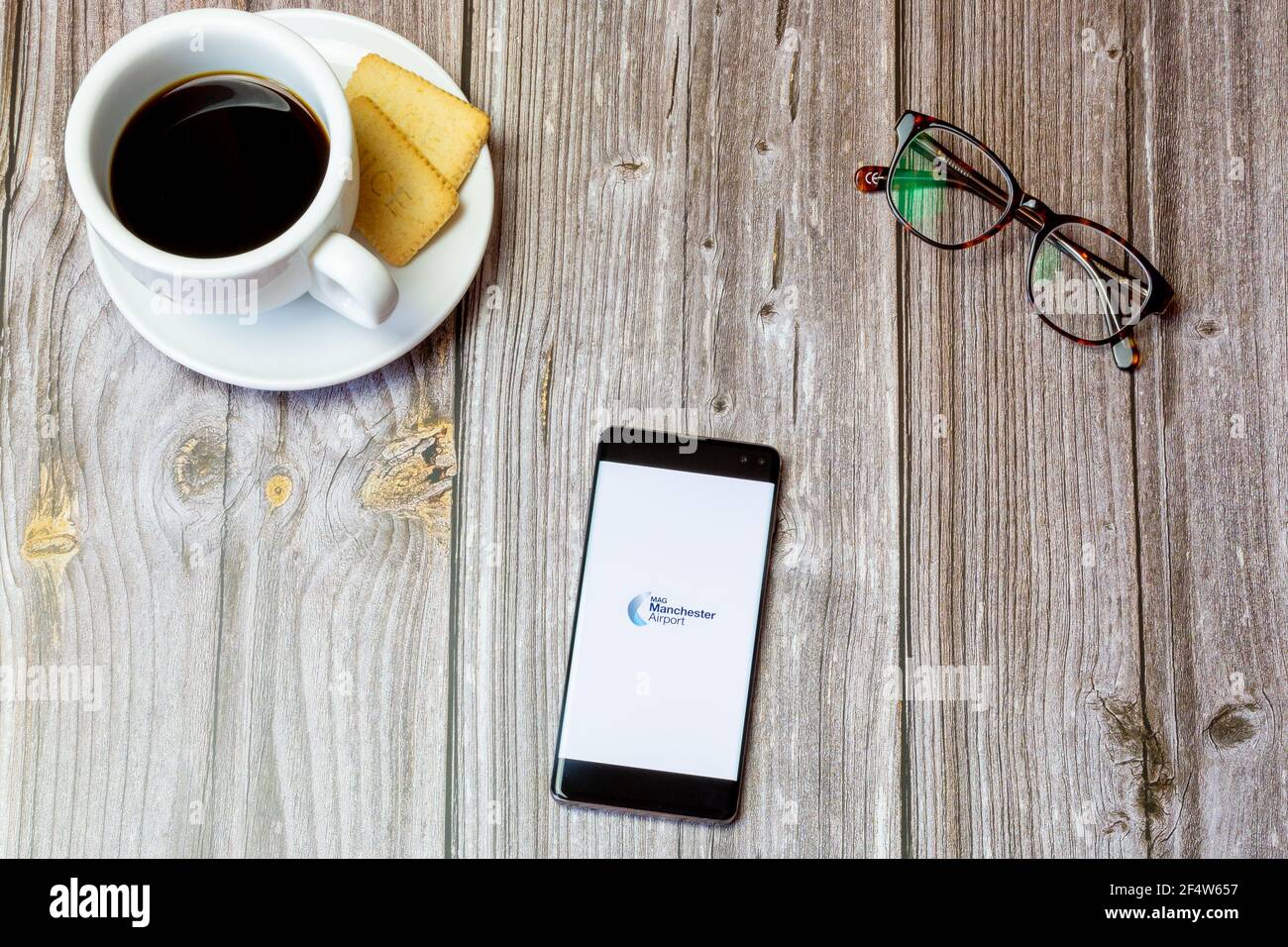 Ein Handy oder Handy auf einem Holz gelegt Tabelle mit der Manchester Airport App auf dem Bildschirm geöffnet Stockfoto