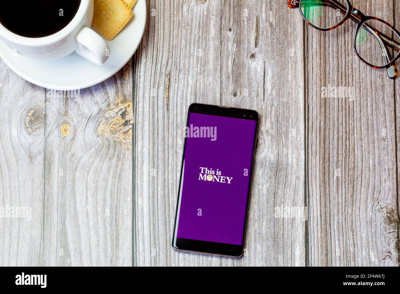 Ein Handy oder Handy auf einem Holz gelegt Tabelle mit der This is Money App auf dem Bildschirm geöffnet Stockfoto