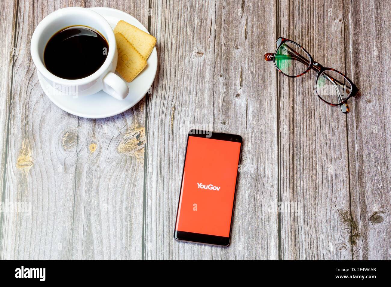 Ein Handy oder Handy auf einem Holz gelegt Tabelle mit der YouGov App auf dem Bildschirm geöffnet Stockfoto