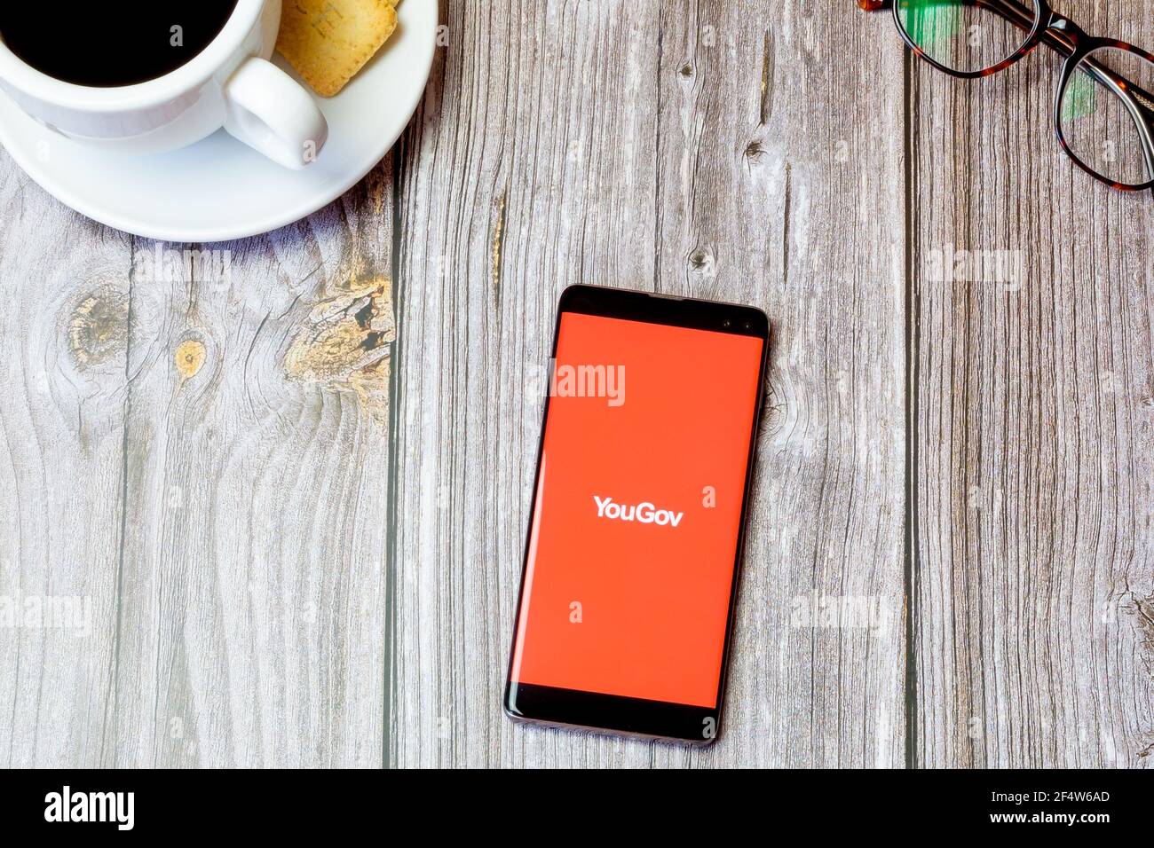 Ein Handy oder Handy auf einem Holz gelegt Tabelle mit der YouGov App auf dem Bildschirm geöffnet Stockfoto