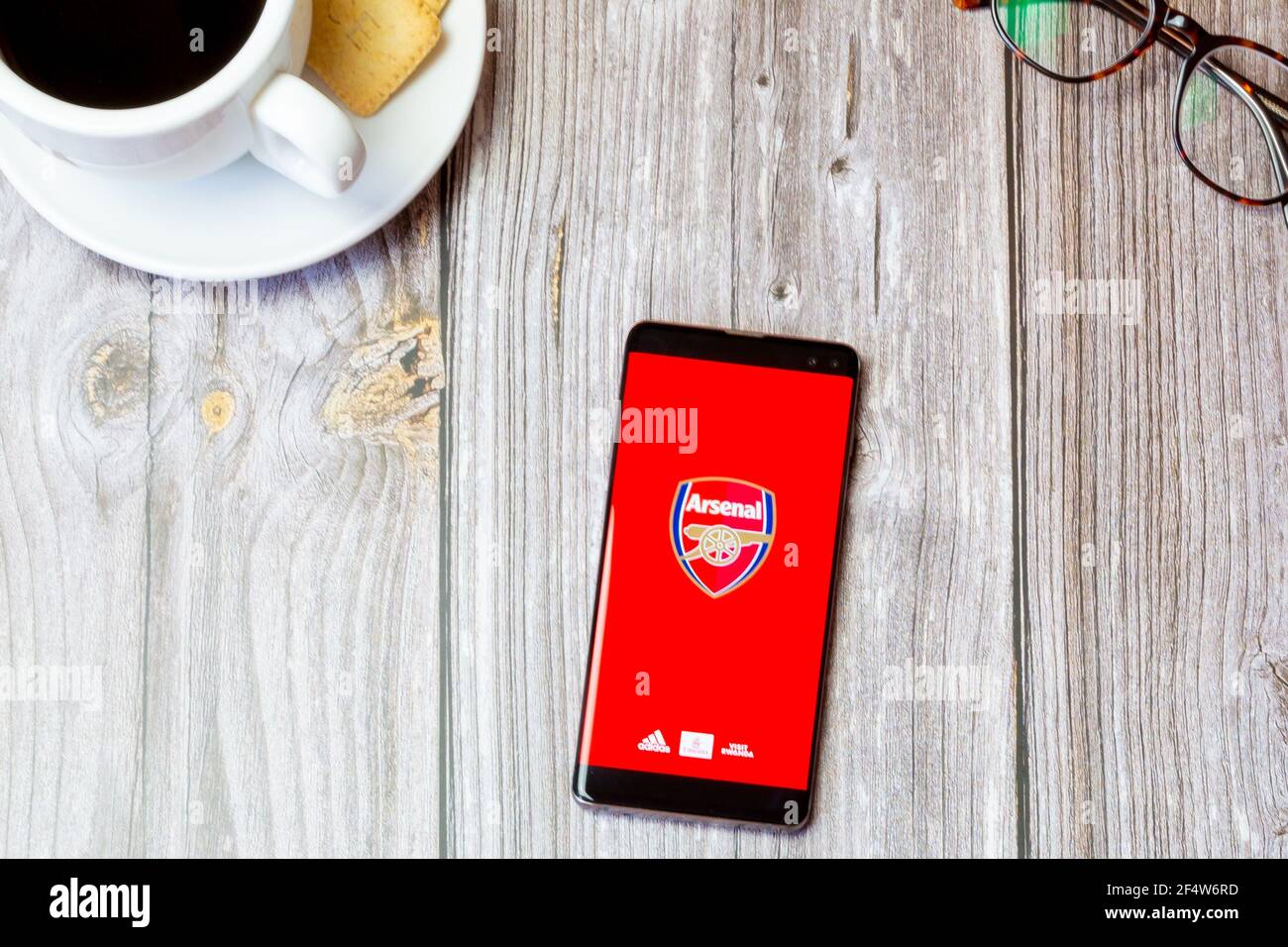 Ein Handy oder Handy auf einem Holz gelegt Tisch mit der Arsenal Football Club App auf dem Bildschirm geöffnet Stockfoto