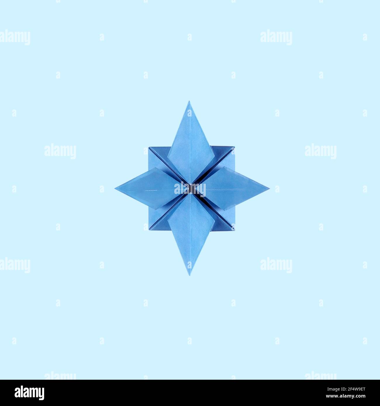 Origami blaues Papier stieg der Winde auf blauem Hintergrund Stockfoto