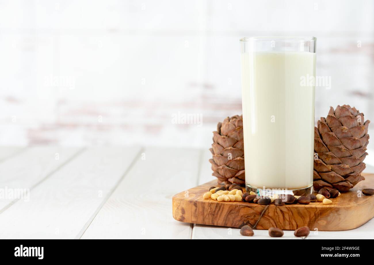 Zedernmilch mit Pinienkernen auf weißem Holztisch Stockfoto