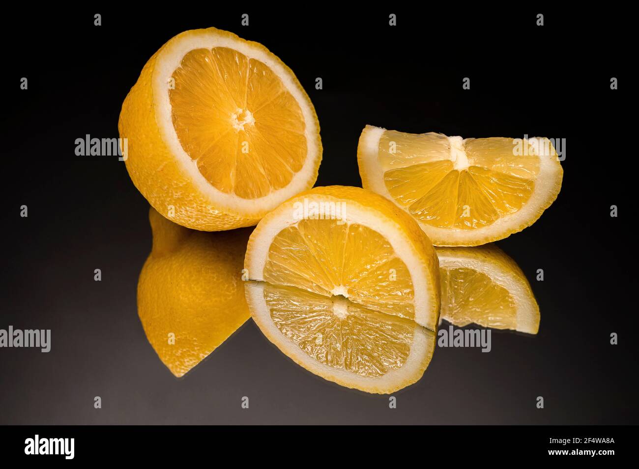 Eine in Scheiben geschnittene Zitrone auf einem Spiegel mit schwarzem Hintergrund Stockfoto