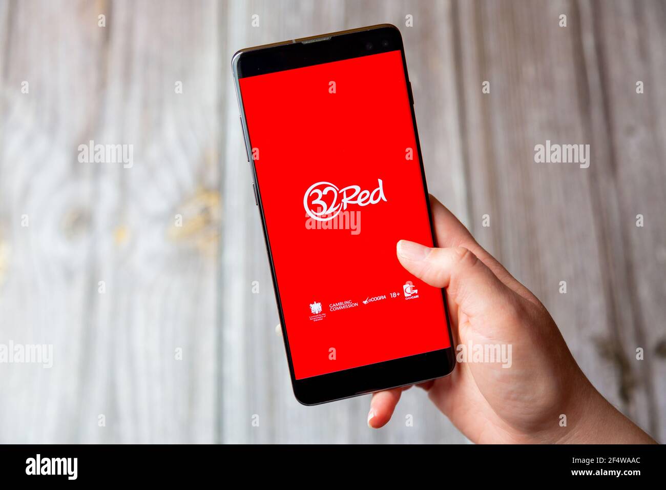 Ein Mobiltelefon oder Mobiltelefon, das in einem gehalten wird Hand mit der 32 Red App auf dem Bildschirm geöffnet Stockfoto