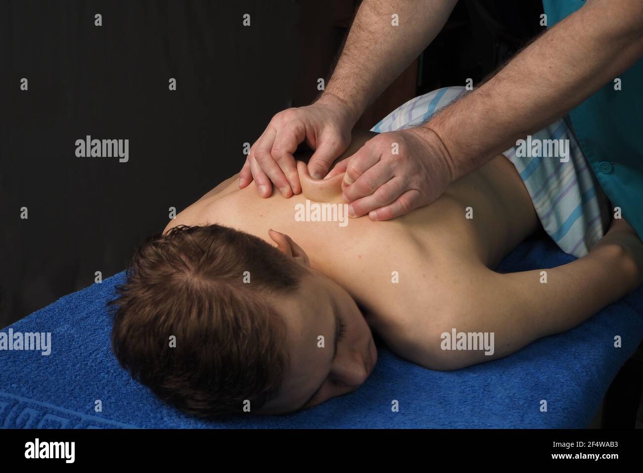 Die Rückenmassage ist manuell. Der Spezialist massiert den Rücken des Patienten auf der Massageliege liegend. Hohe Qualität Stockfoto