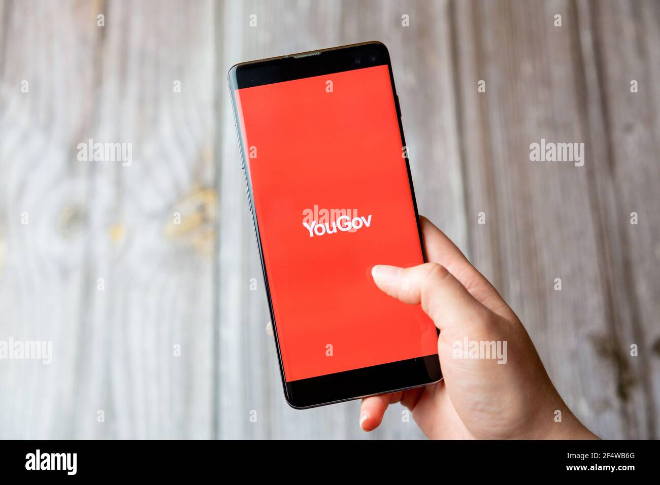 Ein Mobiltelefon oder Mobiltelefon, das in einem gehalten wird Hand mit der YouGov App auf dem Bildschirm geöffnet Stockfoto