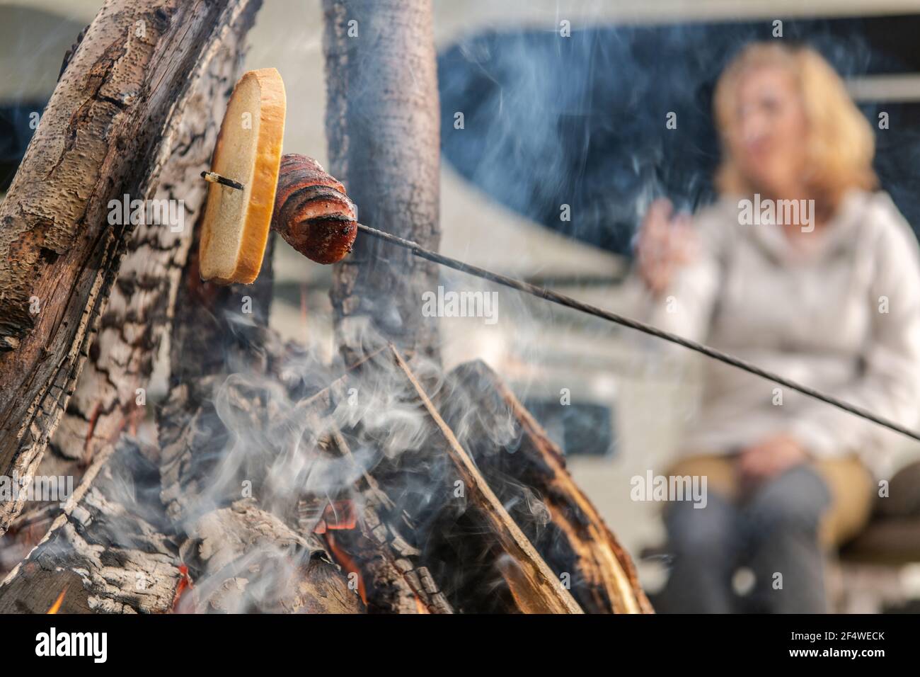 Polnische Wurst und Stück Brot Backen am Lagerfeuer. Outdoor Lifestyle und Camping Theme. Stockfoto