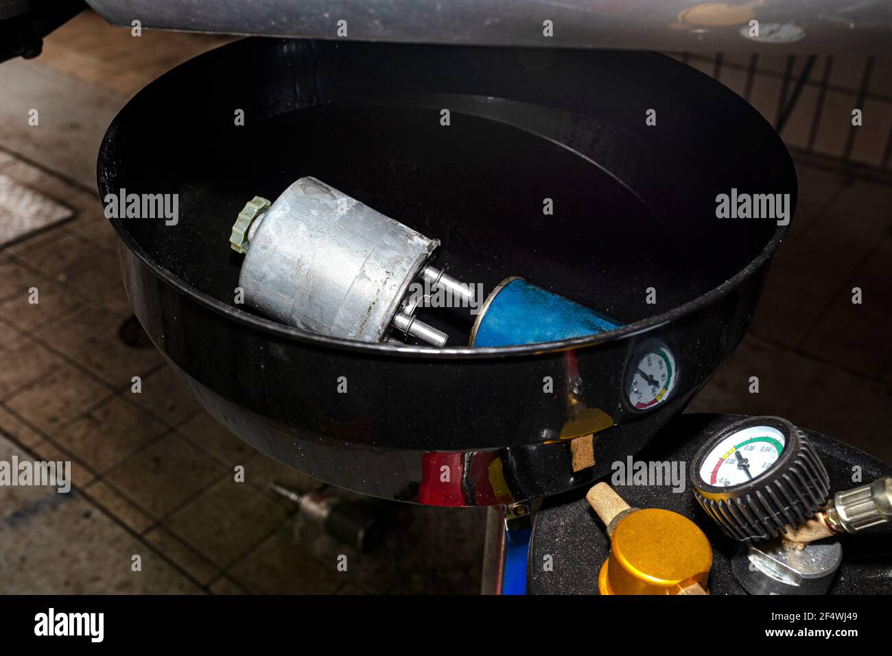 Verschlissener Dieselkraftstofffilter, der im Behälter für Fahrzeugflüssigkeit liegt. Stockfoto