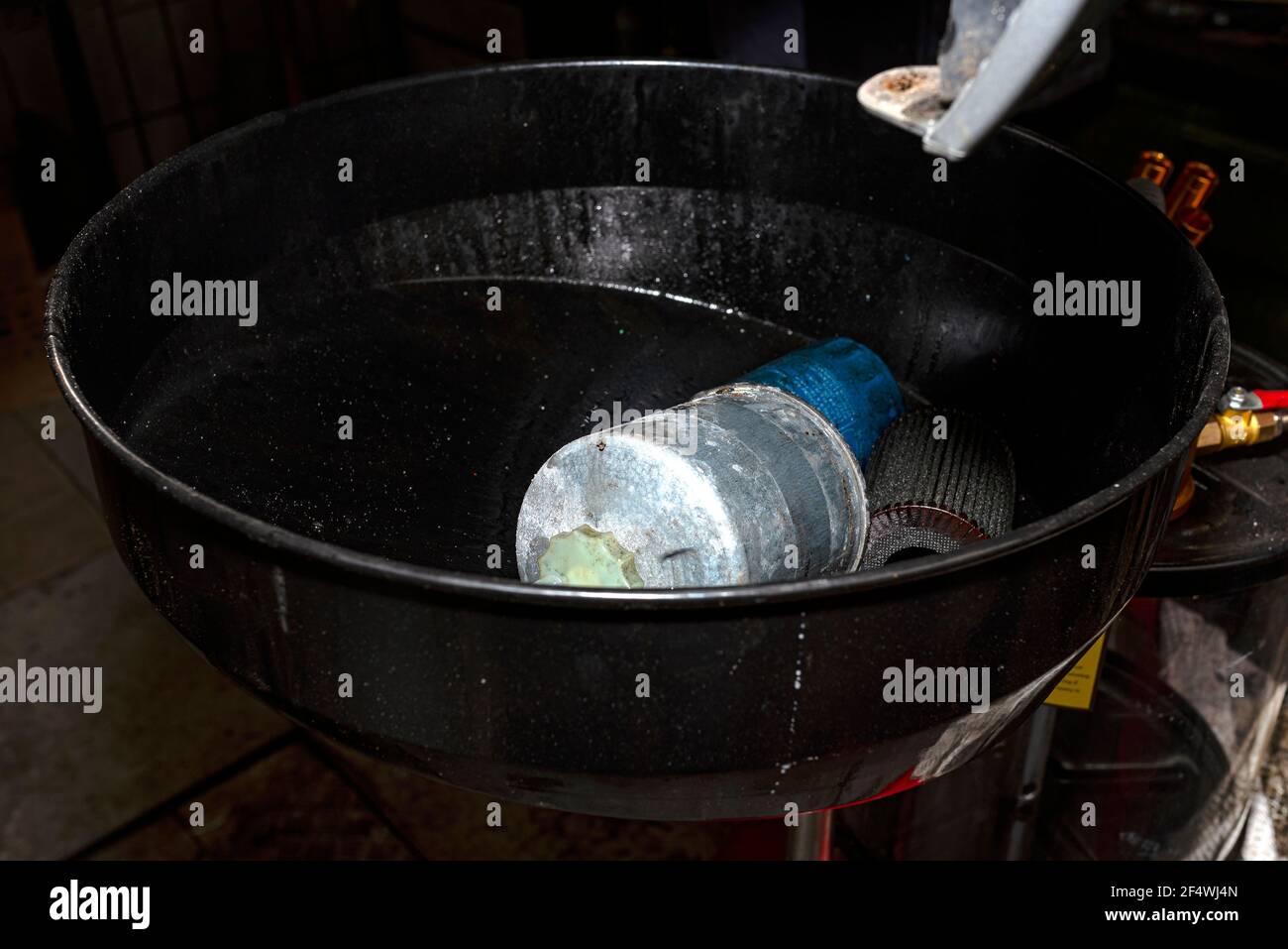 Verschlissener Dieselkraftstofffilter, der im Behälter für Fahrzeugflüssigkeit liegt. Stockfoto