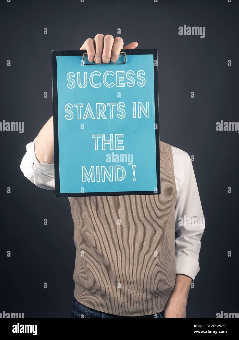 Geschäftsmann hält ein Clipboard, auf dem Erfolg geschrieben wird beginnt Im Kopf Stockfoto