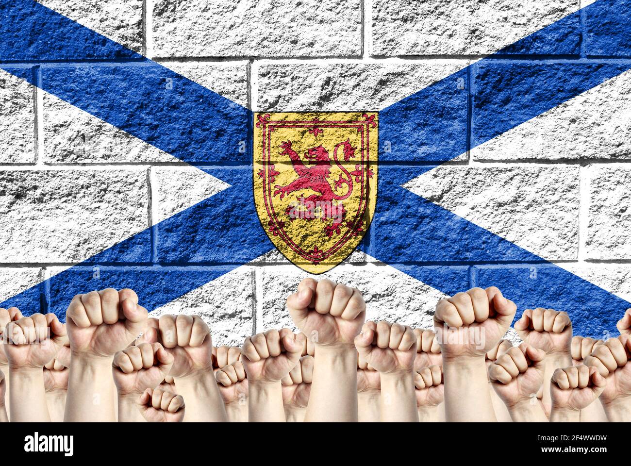 Erhobene Fäuste vor dem Hintergrund der abgebildeten Flagge von Nova Scotia auf einer Ziegelwand, ein Konzept von Stärke und Einheit. Stockfoto