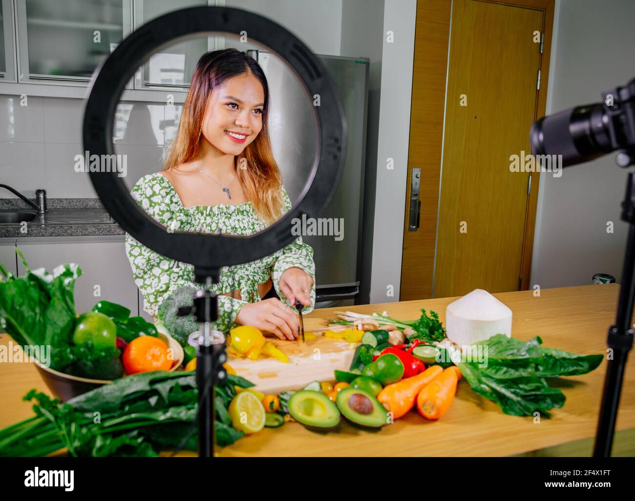 Asiatische Frau Blogger oder Content Creator Kochen und Aufnahme Videokamera. Zeigt gesunde Lebensmittel während der Aufnahme mit Kamera in der Küche. Stockfoto