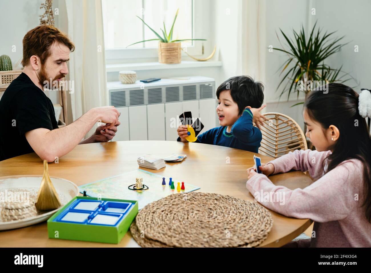 Vater und Kinder spielen mit Karten am Tisch Stockfoto