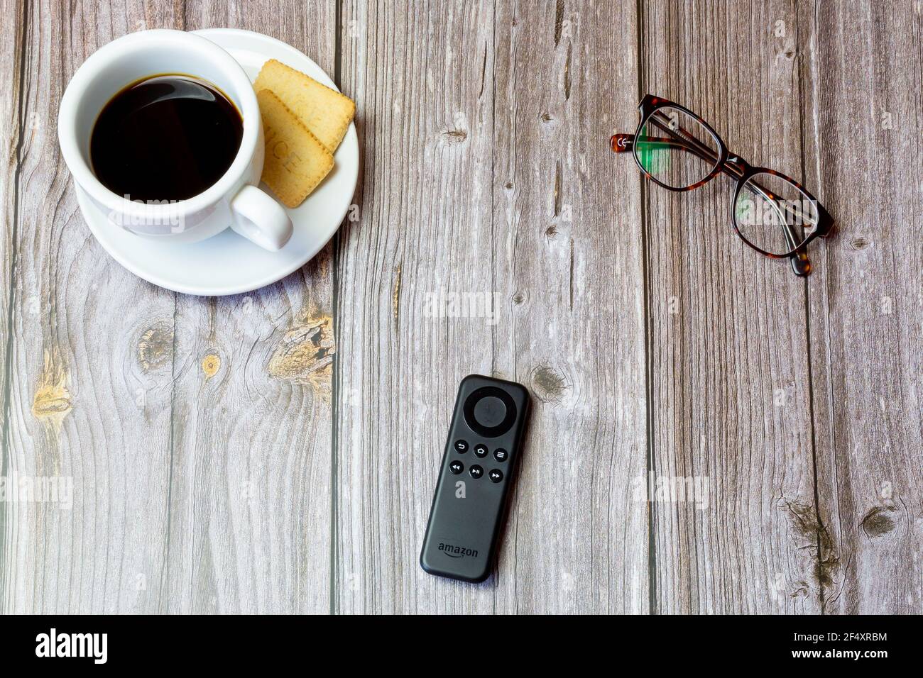 Eine Amazon Feuerlöschstab-Fernbedienung auf einem Holz gelegt Tisch neben Kaffee und Gläsern Stockfoto