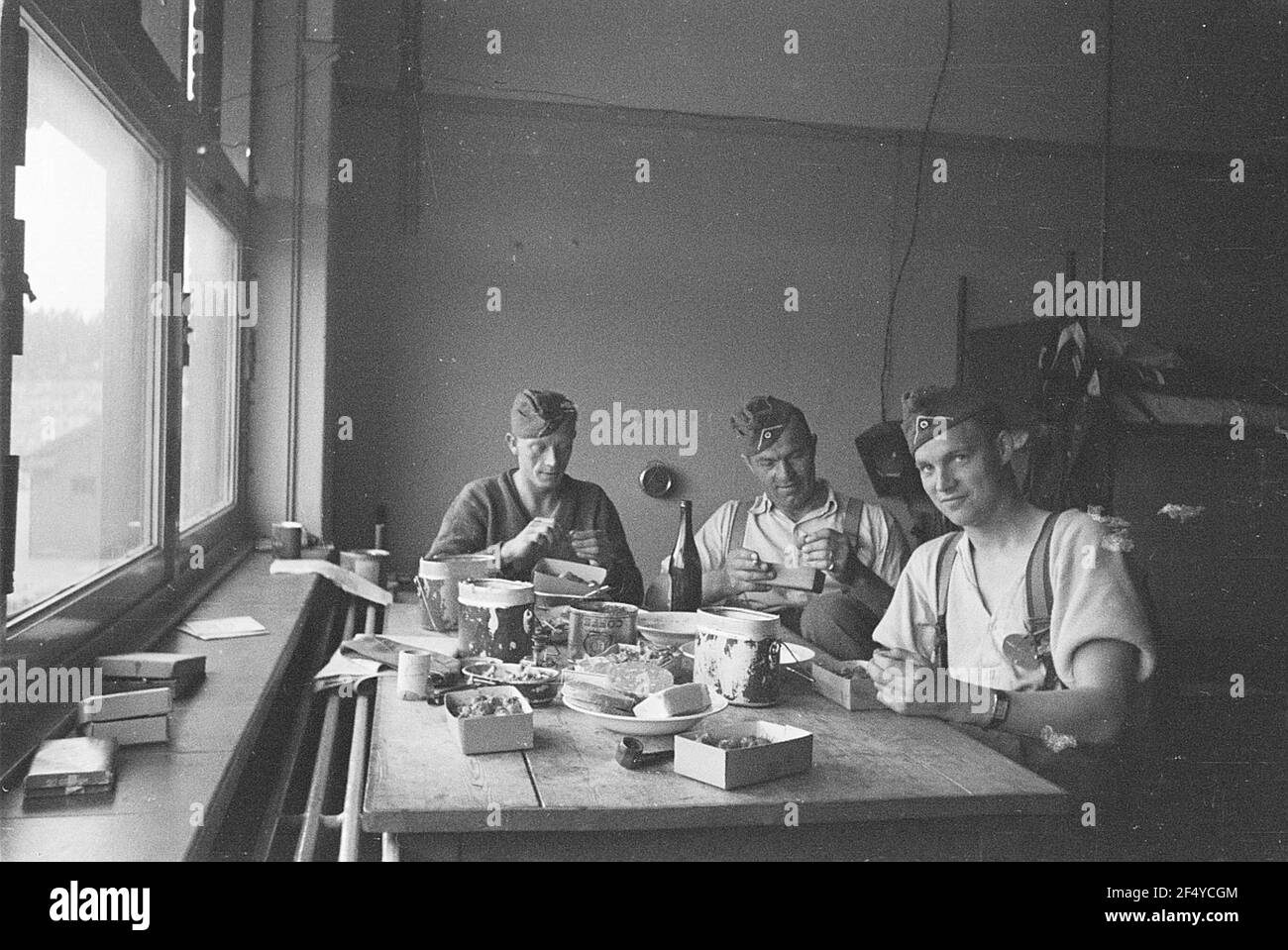 Zweiter Weltkrieg. Niederlande unter deutscher Besatzung. Drei Angehörige der deutschen Wehrmacht in einer Unterkunft am Tisch beim Essen (wahrscheinlich in Den Haag) Stockfoto