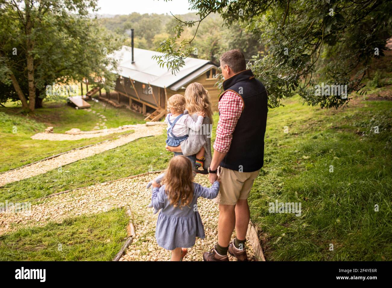 Familie zu Fuß auf dem Weg über Hütte im Wald Stockfoto