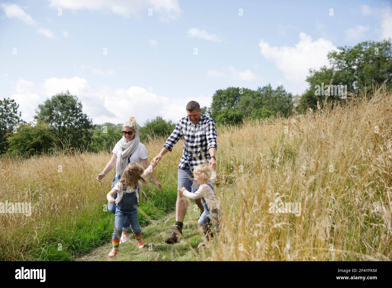 Glückliche Familie läuft in sonnigen ländlichen Feld Stockfoto