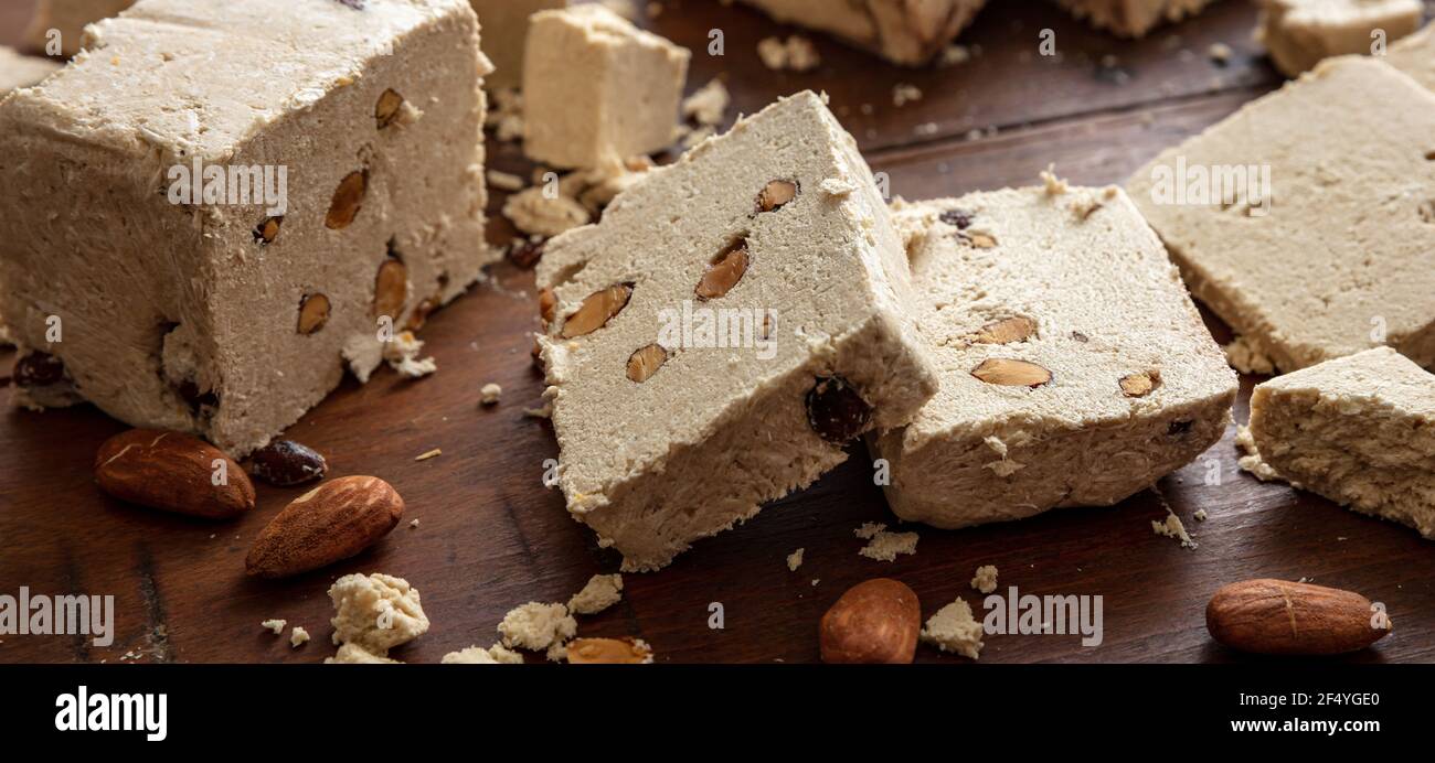 Halva Sonnenblume und Mandeln auf Holztisch Hintergrund. Vanillehalvah oder Halwa Stücke mit Nüssen, Nahaufnahme, kopieren Raum. Traditionelle Dessertkonfektion Stockfoto