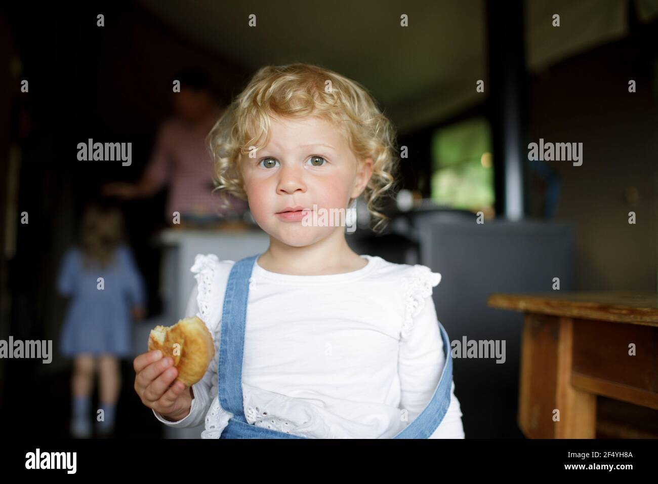Portrait nettes Mädchen mit lockigen blonden Haaren essen Keks an Zu Hause Stockfoto