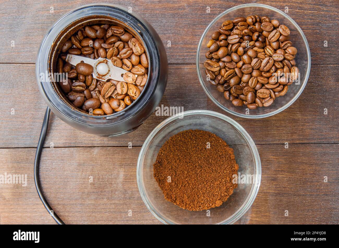 Kaffeebohnen in der Mühle und gemahlener Kaffee in der Schüssel auf dem dunklen Hintergrund Draufsicht Stockfoto