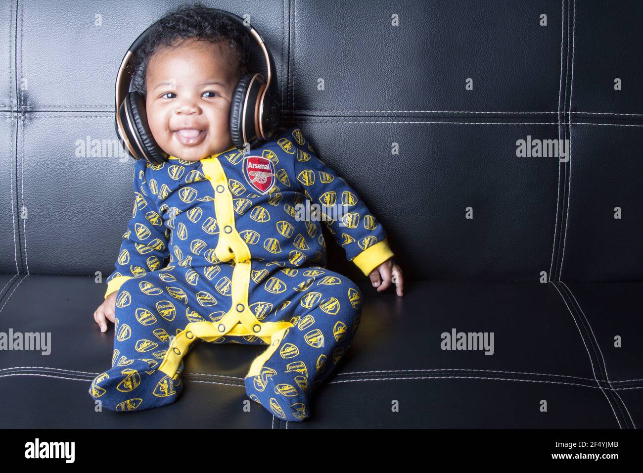 Niedlicher Arsenal Baby Boy Fußballfan trägt sein Lieblings Arsenal Baby-Grow Stockfoto